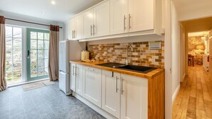Una cocina moderna con armarios blancos, encimera de madera y salpicadero de azulejos.