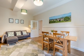 A living room with a sofa, a dining table with chairs, a rug, and a painting on the wall. - 2 Bed in Ludlow (oc-d31885) (Ludlow)