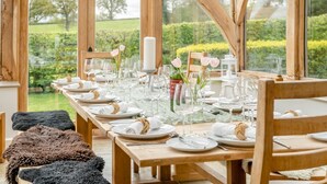 Une table à manger dressée pour six personnes, avec de la vaisselle transparente, des assiettes blanches et un chandelier en guise de centre de table.