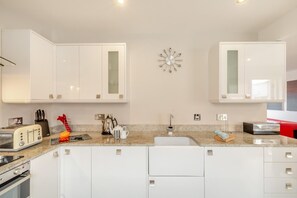 Eine moderne Küche mit weißen Schränken, einer Arbeitsplatte aus Granit und einer Spüle aus Edelstahl.