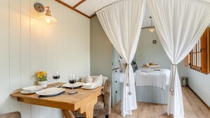Une pièce chaleureuse avec une table en bois dressée pour le repas, un lit à baldaquin et une lampe fixée au mur.