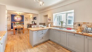 Een moderne keuken met grijze kastjes, een houten kookeiland en een groot raam voor natuurlijk licht.