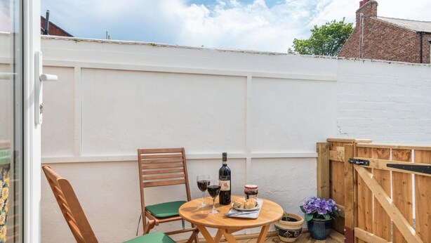 A small patio with a table, two chairs, a bottle of wine, a jar of jam, and a potted plant. - 2 Bed in Saltburn-by-the-Sea (oc-cl004) (Saltburn-by-the-Sea)