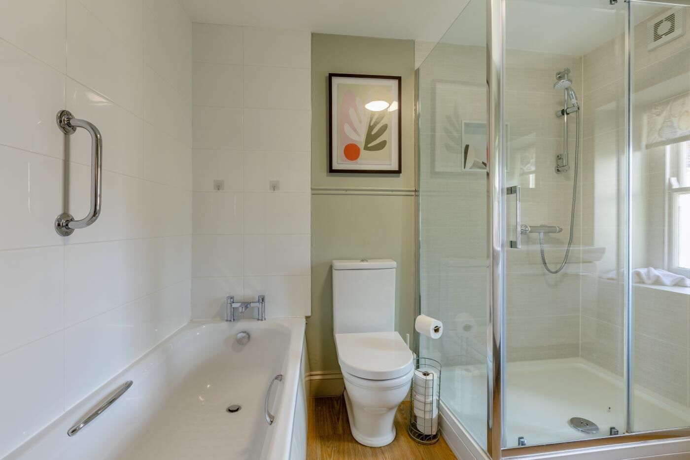 A modern bathroom with a bathtub, toilet, and glass-enclosed shower area.