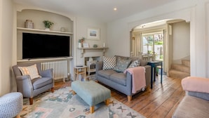 A living room with a television, sofas, a fireplace, and a staircase. - 3 Bed in Lyme Regis (oc-s31839) (Lyme Regis)