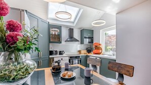 Een moderne keuken met een glazen tafel, een koffiezetapparaat en een bloevas.