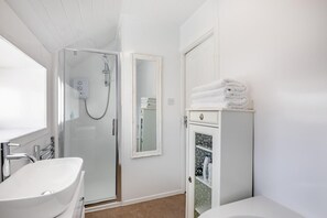 A modern bathroom with a walk-in shower, a white sink, and a cabinet with toiletries.