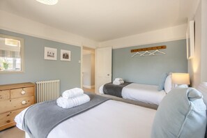 Ein Hotelzimmer mit zwei Betten, einem Schminktisch, einem Heizkörper und einem Fenster mit Jalousien.