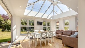 A conservatory with a glass roof, a dining area with a table and chairs, and a sofa. - 3 Bed in Reydon (oc-brae) (Reydon)