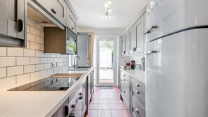 Eine moderne Küche mit grauen Schränken, einem Edelstahlkühlschrank und einem großen Fenster.