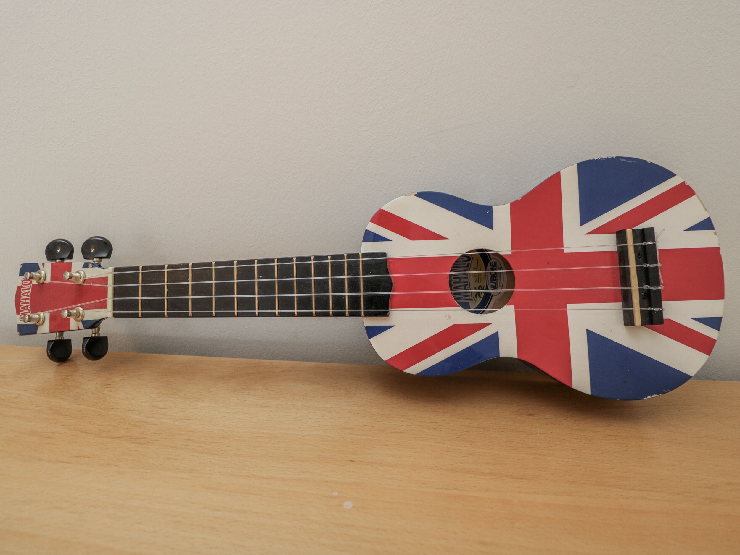 A ukulele with a Union Jack design, a pickguard, and a headstock with tuning pegs.