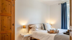 Ein Schlafzimmer mit Bett, Nachttisch, Lampe und einem Korb mit Frühstücksgebäck.