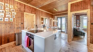 A wooden interior with a kitchen island, wooden flooring, and a dining area with a view. - 3 Bed in Barmouth (oc-c31942) (Barmouth)