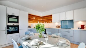 Una cocina moderna con armarios blancos, una pared decorativa de madera y un comedor listo para una comida.