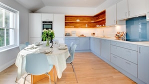 Una cocina moderna con armarios azul claro, un muro decorativo de madera y una zona de comedor con mesa para cuatro.