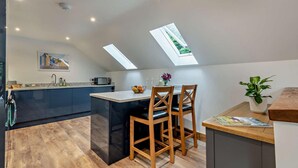 Een moderne keuken met een centraal eiland, donkere kastjes en een dakraam.