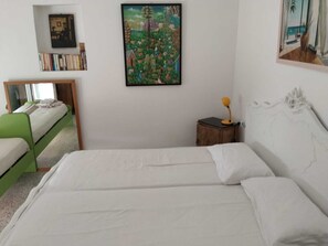 A bedroom with a bed, a bedside table with a lamp, a bookshelf, and a painting on the wall. - Country house in an olive grove, 8 km from the Ionian Sea (Bernalda)