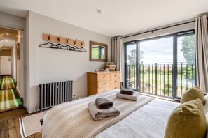 Ein Schlafzimmer mit einem großen Bett, einem Schminktisch, einem Heizkörper, einem Fenster mit Aussicht und einem Kleiderständer mit Kleiderbügeln.