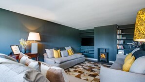 A living room with a sofa set, a fireplace, and a bookshelf. - 5 Bed in Walberswick (oc-lev) (Walberswick)