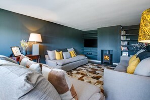 Ein Wohnzimmer mit einer Sofagarnitur, einem Kamin und einem Bücherregal.