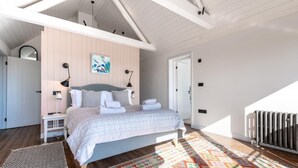 A bedroom with a bed, bedside tables, a radiator, and a colorful rug. - 5 Bed in Walberswick (oc-lev) (Walberswick)