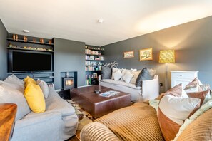 Ein modernes Wohnzimmer mit einer Couch, einem Couchtisch, einem Kamin, einem Bücherregal und einem Flachbildfernseher.