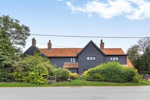 A two-story house with a dark facade, red-tiled roof, and multiple chimneys. - 5 Bed in Walberswick (oc-lev) (Walberswick)