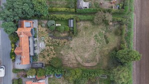 Vista aérea de una zona residencial que muestra una casa, un camino de entrada y un amplio campo cubierto de hierba.
