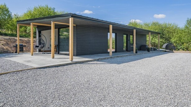 Un edificio moderno con un patio cubierto, zona de barbacoa y una silla colgante.