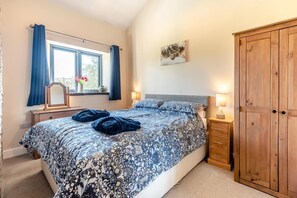 Ein Schlafzimmer mit einem Bett, Nachttischen, einem Kleiderschrank und einem Fenster mit Vorhängen.