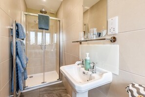 Un baño moderno con cabina de ducha de vidrio, un lavabo blanco y un espejo encima.