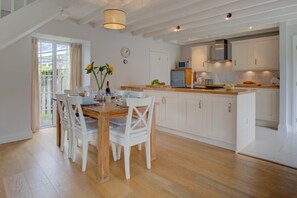 Een moderne keuken met witte kasten, een houten eettafel en een groot raam.