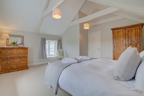 Een slaapkamer met een bed, een kaptafel, een stoel en een houten garderobe.