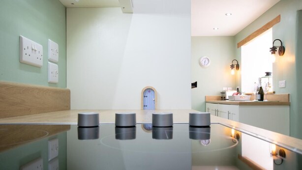 Un baño moderno con ducha de vidrio, banca de madera y tocador con espejo e iluminación.