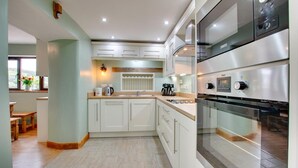 Una cocina moderna con armarios blancos, horno empotrado y ventana con vistas al exterior.