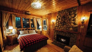 Une pièce chaleureuse dans un chalet en bois, avec un lit, une cheminée en pierre et un mur en pierre.
