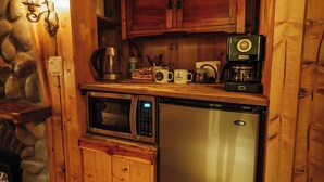 Une cuisine compacte avec des murs en bois, un four à micro-ondes, une machine à café et un réfrigérateur.