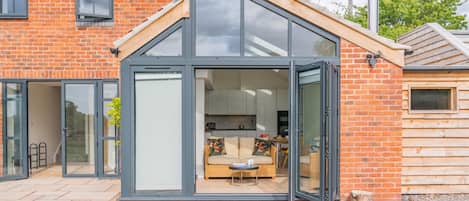 A modern house with a glass conservatory, a brick exterior, and a visible kitchen area.