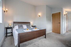Une chambre à coucher avec un lit en bois, deux tables de chevet, une commode, une porte et un luminaire fixé au mur.