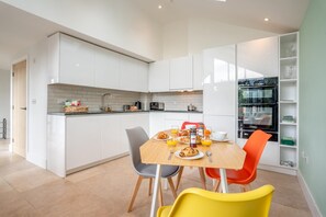 A modern kitchen with white cabinets, a dining table with chairs, and a breakfast setting. - 2 Bed in Thornton Le Moor (oc-h31952) (Thornton-le-Moor)