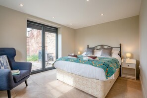 A bedroom with a bed, a chair, a nightstand, and a sliding glass door leading to an outdoor area. - 2 Bed in Thornton Le Moor (oc-h31952) (Thornton-le-Moor)