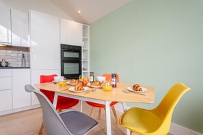 A compact kitchen with white cabinets, a black oven, and a dining table with breakfast items. - 2 Bed in Thornton Le Moor (oc-h31952) (Thornton-le-Moor)