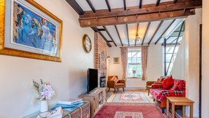 A cozy living room with a fireplace, a television, and a red sofa. - 3 Bed in Hythe (oc-o31997) (Hythe)