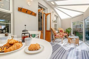 A cozy breakfast setting with croissants, a coffee pot, and wicker chairs. - 3 Bed in Hythe (oc-o31997) (Hythe)