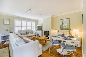 Ein stilvolles Wohnzimmer mit Sofa, Couchtisch und Essbereich mit Stühlen und einem Tisch für zwei Personen.
