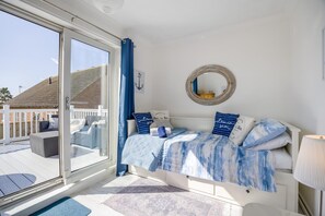 Quarto com cama, mesa de cabeceira, abajur, janela e vista para o exterior.