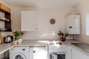 A compact kitchen with a washing machine, a stove, and a water heater. - 1 Bed in Catton (oc-b31984) (Catton)