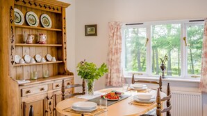 A dining room with a wooden buffet, a table set for four, and a window with a view of trees. - 1 Bed in Catton (oc-b31984) (Catton)