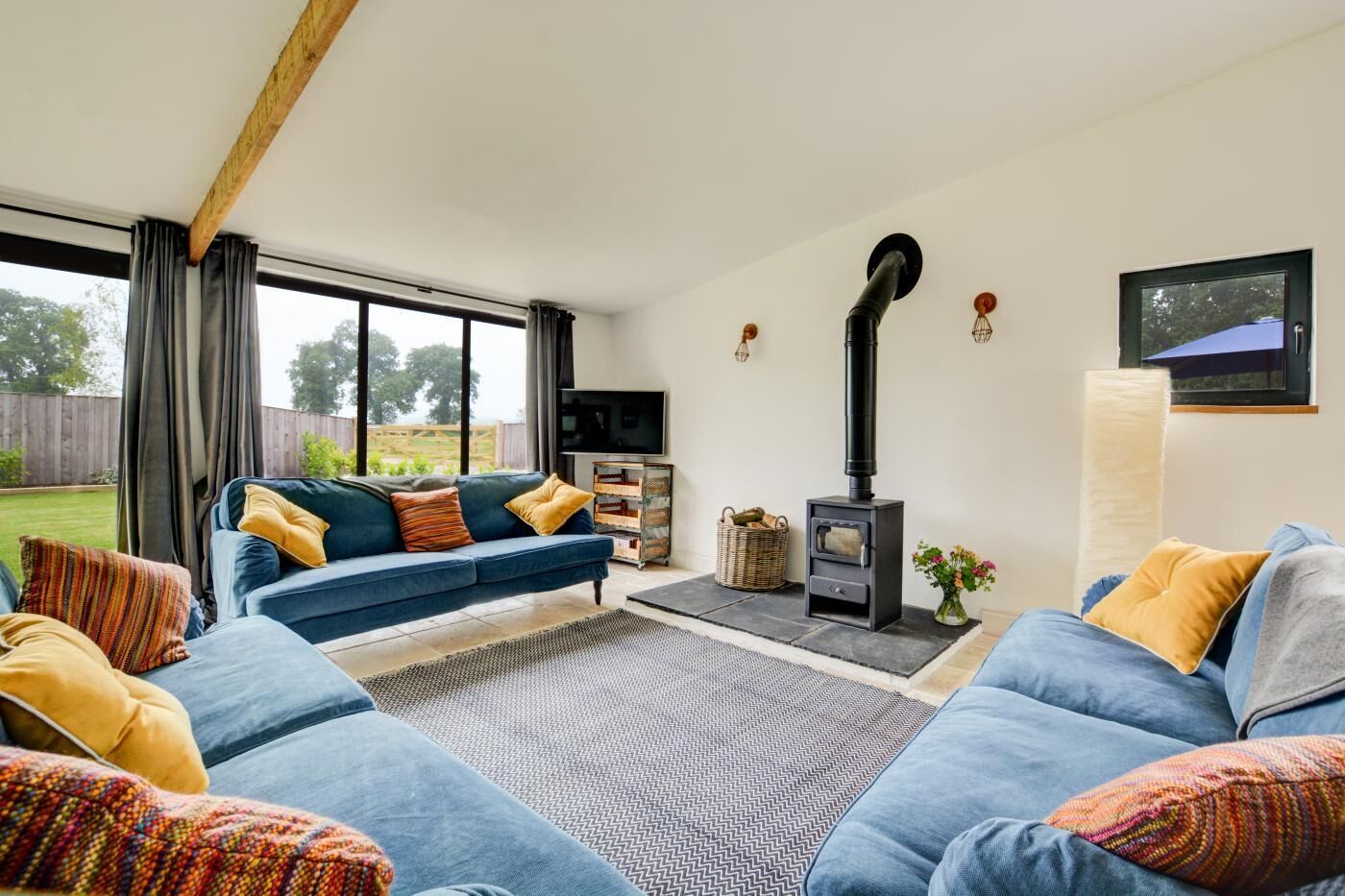 A living room with a sofa set, a fireplace, a television, and a view of the outdoors.
