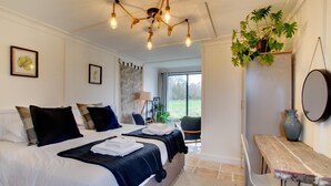 Ein Schlafzimmer mit zwei Betten, einer hölzernen Bank, einem Spiegel und einem Blumentopf.